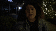 a woman in a denim jacket is standing in the dark and the word shagarita is on the bottom