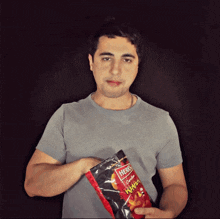 a man is holding a bag of herbs ramen flavored chips
