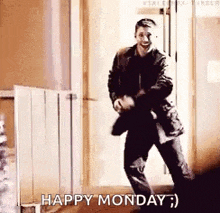 a man in a suit is dancing in a hallway with the words `` happy monday '' .