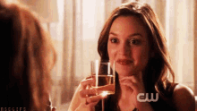 a woman holding a glass of wine with a cw logo on the bottom