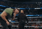 a man in a green tank top is standing in a wrestling ring with a referee