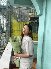 a woman holds a bouquet of flowers in front of a green fence