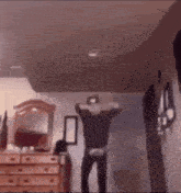 a man is dancing in a room with a dresser and a mirror in the background .