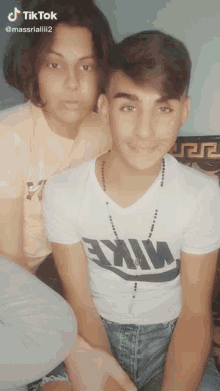 a boy wearing a nike shirt sits next to a girl