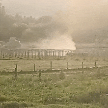 a field with a fence and smoke coming out of it