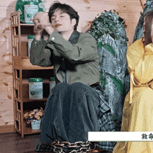 a woman in a yellow dress sits next to a man chained to a chair