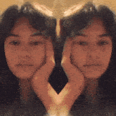 a woman 's face is reflected in a mirror with her hands on her face .