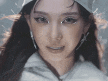 a close up of a woman 's face wearing a white hat and earrings .