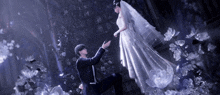 a man is kneeling down in front of a bride in a white dress