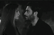 a black and white photo of a man and woman kissing .