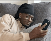 a man is laying on a couch looking at his cell phone