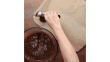 a person is mixing chocolate in a bowl with a spatula .