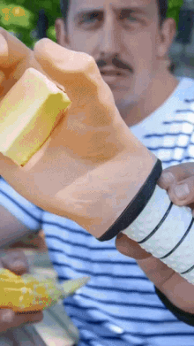 a man in a striped shirt is holding a piece of butter