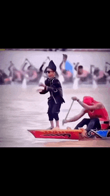 a boy in a costume is standing on a boat in the water .