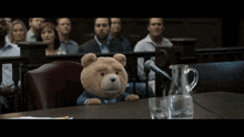 a group of people sitting around a table with a teddy bear on the floor