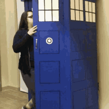 a woman stands in front of a blue door that looks like a tardis