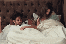 a man and a woman are laying in bed under a blanket with a pillow that says " i love you " on it