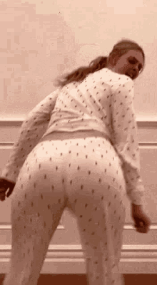 a woman in pajamas is dancing in front of a wall in a room .