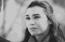 a black and white photo of a woman crying and looking at the camera .
