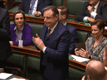 a man in a suit and tie is clapping his hands in a parliament