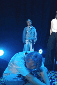 a man in a denim jacket is kneeling down in front of a microphone