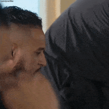 a man with a beard is kissing another man 's neck .