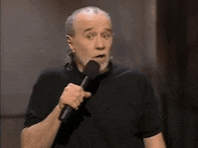 a man in a black shirt is holding a microphone in his mouth