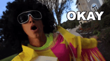 a man wearing sunglasses and a wig says " okay "