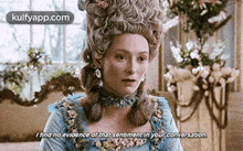 a woman in a blue dress and wig is talking to another woman in a room .