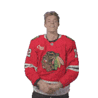 a man wearing a chicago blackhawks jersey holds his arms up in the air