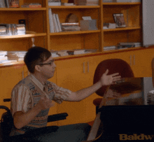 a man in a wheelchair sitting in front of a baldw desk
