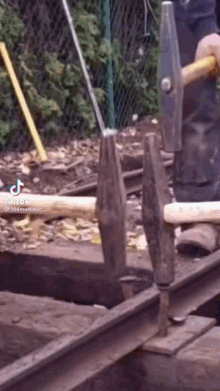 a person is holding a hammer and a pair of hammers on a train track