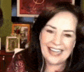 a woman wearing headphones is smiling while sitting in front of a picture frame .