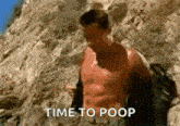 a shirtless man is standing on top of a rocky hill with the words `` time to poop '' written on the bottom .
