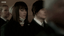 a woman with a collar around her neck is standing in a crowd with bbc written on the bottom right