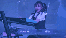 a girl playing a keyboard that says roland on the front