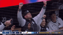 a man with his arms in the air watches a baseball game between the tigers and the yankees