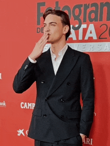 a man blowing a kiss on a red carpet in front of a sign that says fotogran