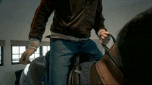 a man in a brown jacket is standing on a chair