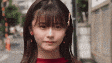 a close up of a woman wearing earrings and a red shirt