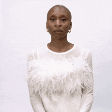 a woman in a white top with feathers on the sleeves