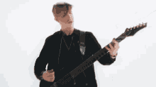 a man in a black jacket is playing a guitar .