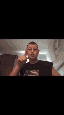 a man wearing glasses and an american flag shirt looks at the camera