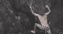 a man in floral shorts is climbing up a rock wall