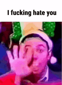 a man wearing a santa hat is covering his face with his hand and says `` i fucking hate you '' .