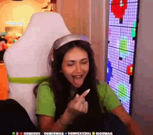 a woman in a green shirt is sitting in a chair and making a funny face .