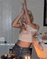 a woman in a crop top and jeans is standing in front of a bouquet of flowers .