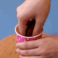 a person is holding a pink polka dot cup