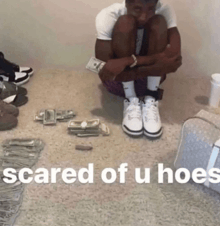 a man is kneeling on the floor with a stack of money in front of him and the words scared of u hoe on the bottom