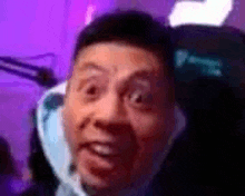 a close up of a man making a funny face while sitting in a chair .